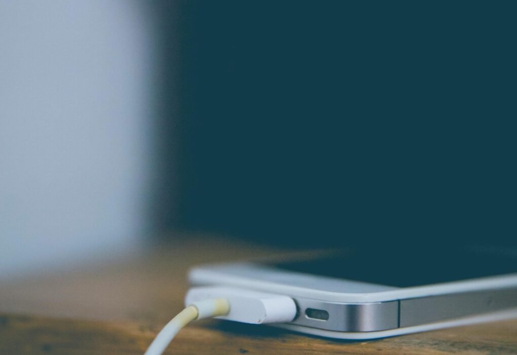 Meistras prijungęs kraunamą išmanųjį telefoną ant medinio stalo