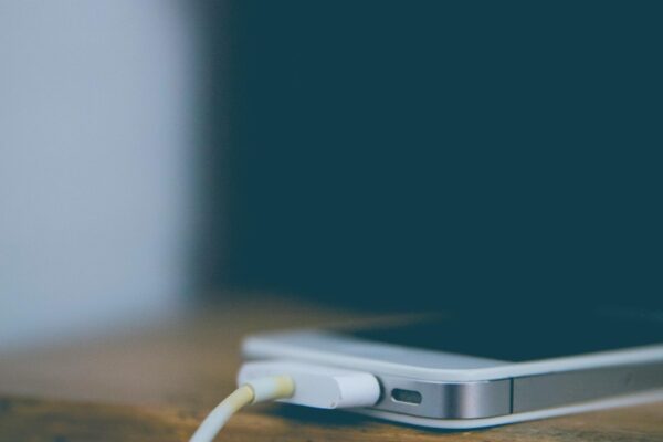 Meistras prijungęs kraunamą išmanųjį telefoną ant medinio stalo