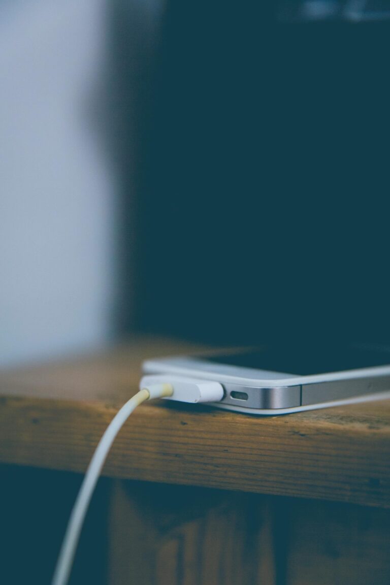 Meistras prijungęs kraunamą išmanųjį telefoną ant medinio stalo